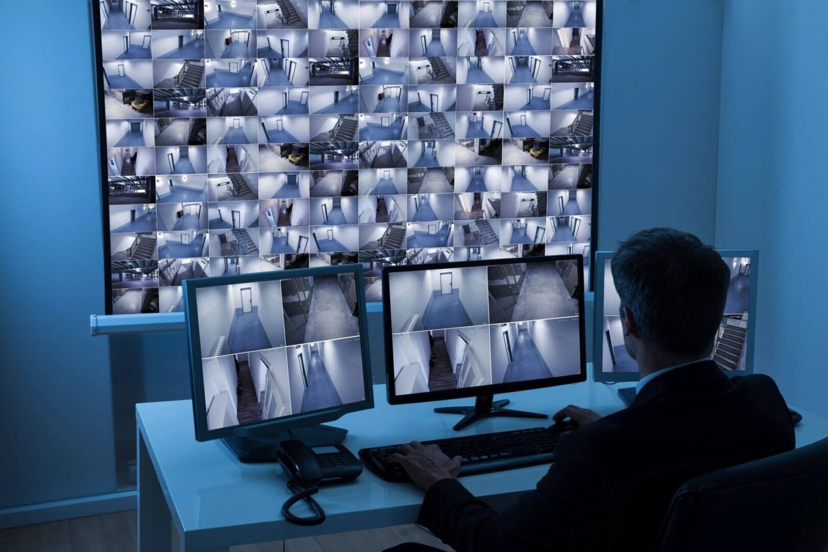 A man sitting at his desk looking at multiple monitors.